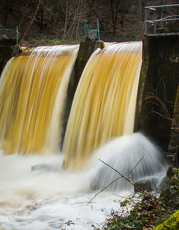 Water colored by silt after heavy rains pours over spillway. Lithia Park Ashland Oregon